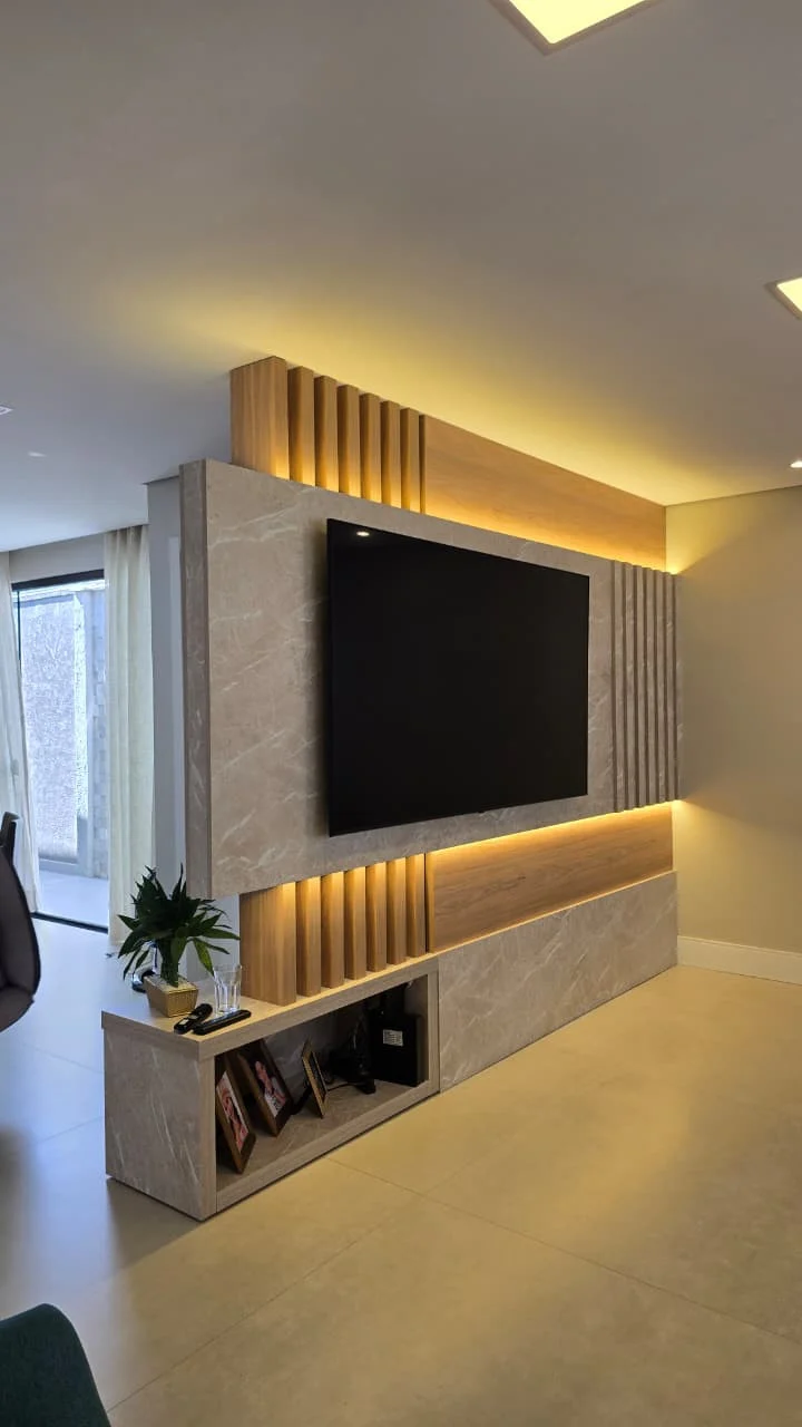 Painel de TV em porcelanato marmorizado com faixas de ripado em madeira e iluminação embutida em fita